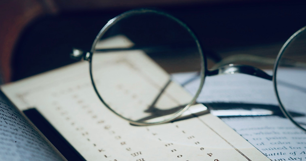 本の上に置かれたメタルフレームの丸眼鏡