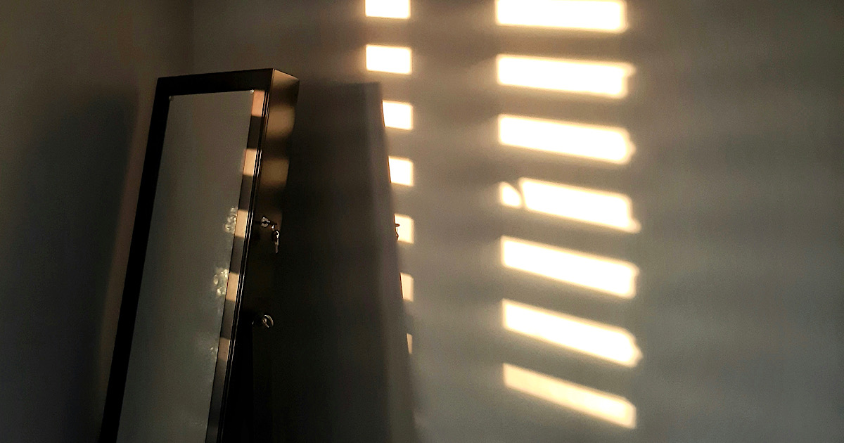 窓から差し込む光が壁や鏡を照らしている部屋の様子