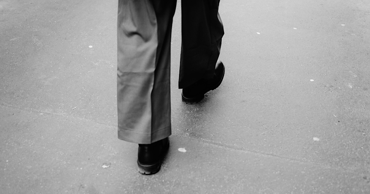 スラックスを穿いて歩く人の足元の後ろ姿