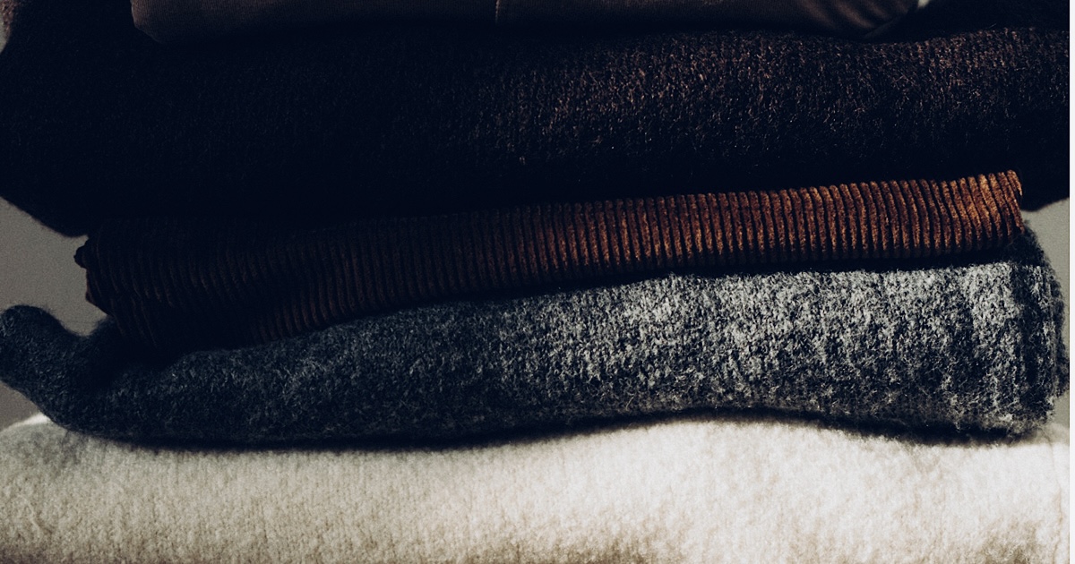 畳んで重ねられた冬物の洋服を撮影した様子