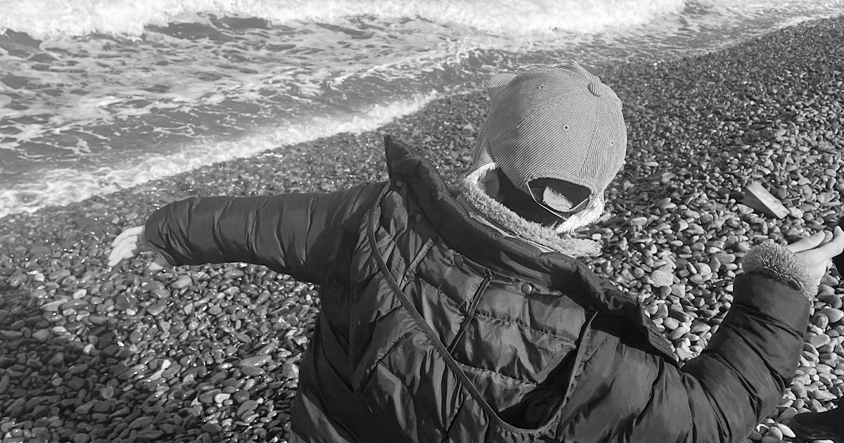 海岸沿いで海に向かって石を投げる子供