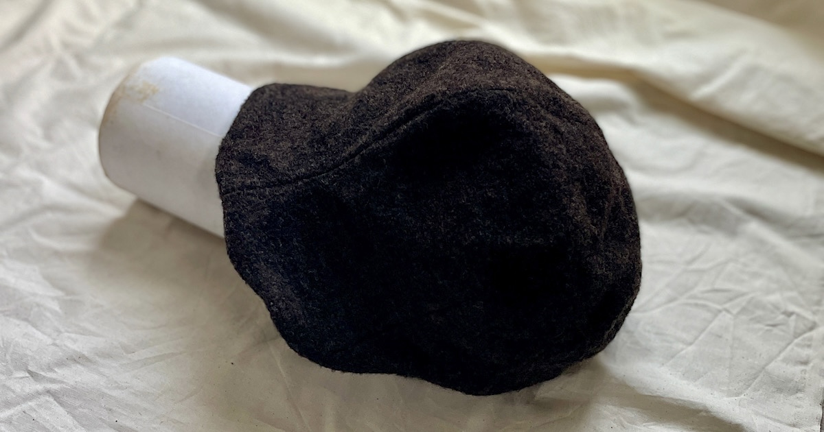 生成りのシーツの上に置かれたブラウンのキャスケット