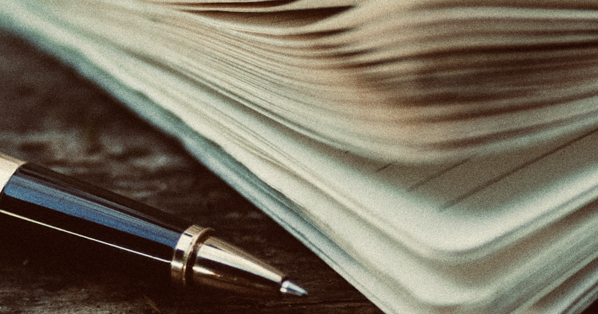 木製のテーブル上に置かれたペンとノート