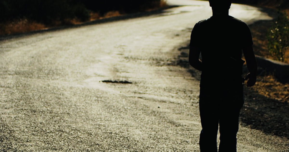 アスファルトの道を歩く男性