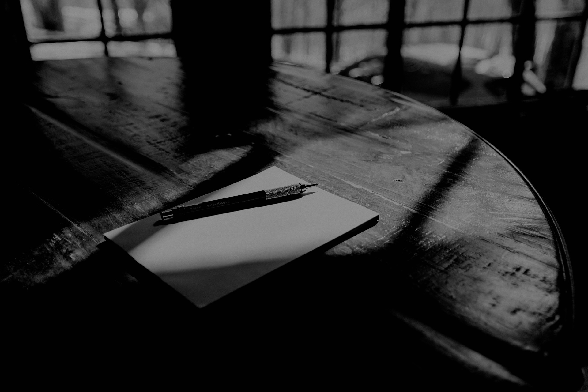 木製の丸いテーブルの上に置かれたノートとペン